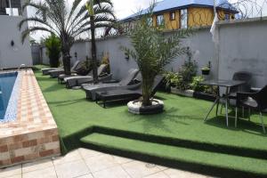 un patio trasero con césped verde y piscina en Golden Tulip Hotel -GT31 Stadium Road en Port Harcourt