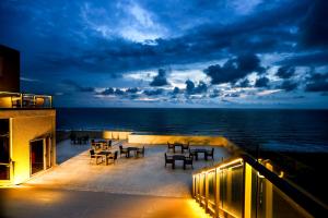 a balcony with tables and chairs and the ocean at night at Corundum Breeze Negombo in Negombo