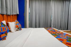 a bedroom with a large white bed with colorful pillows at FabHotel Royal Orbits in Surat