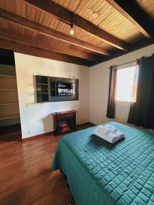 a bedroom with a bed and a tv on the wall at Apartamentos Dumont in Monte Verde