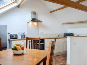 a kitchen with a wooden table with a bowl of vegetables on it at Criffel Cottage in Ruthwell
