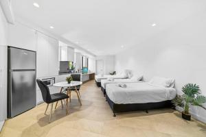 a bedroom with two beds and a table and a kitchen at Lovely Studio apartments in Strathfield CBD in Sydney