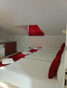 a room with three white beds with red pillows at ÇARŞI HOTEL&CAFE in Trabzon