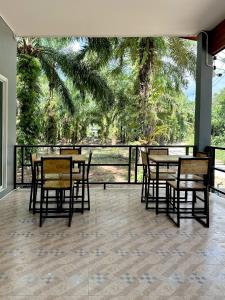 una sala da pranzo con tavoli e sedie e un balcone di Evergreen Guest House a Parco Nazionale di Khao Sok