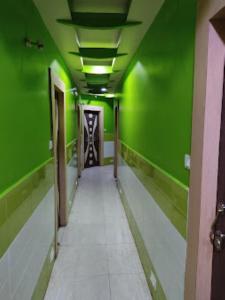 un couloir vide aux murs verts et un couloir aux carreaux blancs dans l'établissement Hotel Delmon,Bhubaneswar, à Bhubaneswar