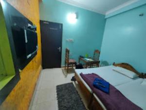 - une chambre avec un lit et une télévision murale dans l'établissement Hotel Delmon,Bhubaneswar, à Bhubaneswar