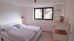 een witte slaapkamer met een bed en een raam bij seenahe Design-Ferienwohnung Loft Aquamarin in Überlingen