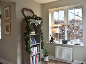 a book shelf with christmas decorations and a window at Poppy House in Kirkoswald