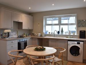 a kitchen with a table and chairs and a dishwasher at Poppy House in Kirkoswald