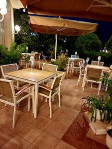 eine Terrasse mit Tischen, Stühlen und einem Sonnenschirm in der Unterkunft Hotel Rosati in Rimini