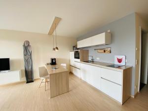 a kitchen with white cabinets and a table at Apartment EigenArt in Owingen