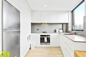 a kitchen with white cabinets and a stainless steel refrigerator at Lovely Studio apartments in Strathfield CBD in Sydney
