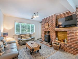 a living room with a brick fireplace with a tv at Poulter Cottage in Elkesley