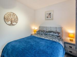 a bedroom with a bed with a blue blanket at Poulter Cottage in Elkesley