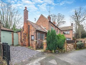 an old brick house with a gate in the driveway at Poulter Cottage in Elkesley