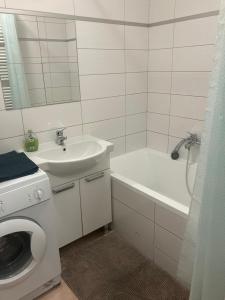 uma casa de banho branca com um lavatório e uma máquina de lavar roupa em Apartment Brno Reissigova em Brno