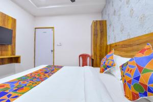 アーメダバードにあるFabHotel Starの白いベッド1台、カラフルな掛け布団が備わるベッドルーム1室が備わります。