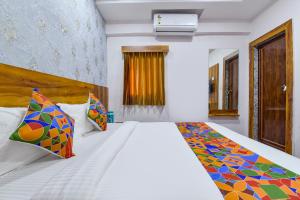 um quarto com uma grande cama branca com almofadas coloridas em FabHotel Star em Ahmedabad