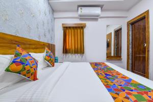 アーメダバードにあるFabHotel Starのベッドルーム(大きな白いベッド、カラフルな枕付)