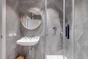 y baño con lavabo y ducha con espejo. en Mamo Florence - La Badessa Apartment, en Florencia