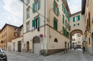 an alley in a city with buildings with green shutters at Mamo Florence - La Badessa Apartment in Florence