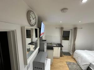 ブロムリーにある1st Studio Flat With full Private Toilet And Shower With its Own Kitchenette in Keedonwood Road Bromley A Fully Equipped Independent Studio Flatのベッドルーム1室(ベッド1台、壁掛け時計付)