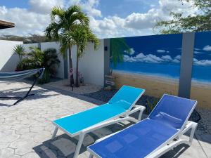 Beautiful luxury villa with private pool في شاطئ بالم إيغل: زوج من الكراسي الزرقاء وطاولة على الفناء