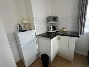 a small kitchen with a white refrigerator and a sink at 1st Studio Flat With full Private Toilet And Shower With its Own Kitchenette in Keedonwood Road Bromley A Fully Equipped Independent Studio Flat in Bromley