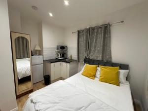 1 dormitorio con cama blanca y almohadas amarillas en 1st Studio Flat With full Private Toilet And Shower With its Own Kitchenette in Keedonwood Road Bromley A Fully Equipped Independent Studio Flat, en Bromley