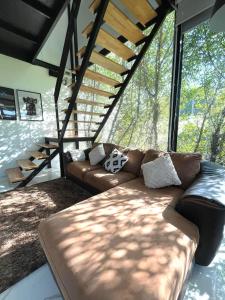 un soggiorno con divano in pelle di fronte a una grande finestra di Peaceful & Contemporary Duplex Escape a Ban Thap Nang