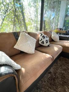 a brown couch with pillows on it in a living room at Peaceful & Contemporary Duplex Escape in Ban Thap Nang