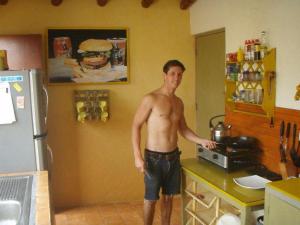 un hombre sin camisa parado en una cocina junto a un mostrador en Hospedaje Punta Hermosa, en Punta Hermosa