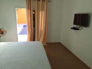 Schlafzimmer mit einem Bett, einem TV und einem Fenster in der Unterkunft Hôtel Colibri in Niaga