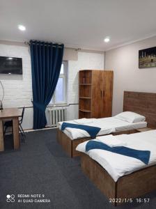een slaapkamer met 3 bedden, een bureau en een tafel bij Ilhombek Guest House Hotel in Tasjkent