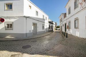 una calle adoquinada vacía con edificios blancos en Casa da Vila nº 6, en São Brás de Alportel
