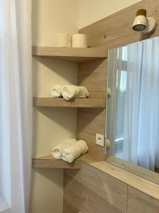 ein Badezimmer mit Holzregalen, Handtüchern und einem Spiegel in der Unterkunft Weißes Haus in Plauen