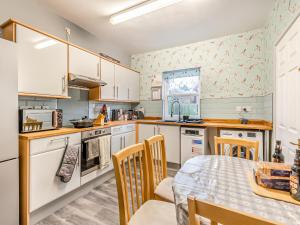 uma cozinha com armários brancos e uma mesa e cadeiras em Horseshoe Cottage em Skegness