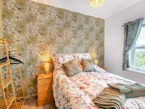 a bedroom with a bed with a floral wallpaper at Horseshoe Cottage in Skegness