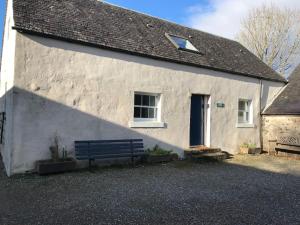 a white building with a bench in front of it at Stable Cottage, Ardnadrochet in Lochdon