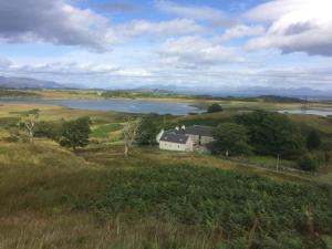 a house in the middle of a field with a lake at Stable Cottage, Ardnadrochet in Lochdon