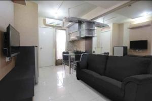 a living room with a black couch and a kitchen at Apartemen kalibata city by Rama Property in Jakarta