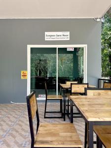 un ristorante con tavoli e sedie in legno di fronte a una finestra di Evergreen Guest House a Parco Nazionale di Khao Sok