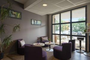 - une salle d'attente avec des chaises violettes et une table dans l'établissement The Originals City, Hotel Novella Premium, Nantes Est, à Carquefou
