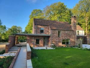 a brick house with a large lawn in front of it at Private Apartment at Woodland Retreat in Gamlingay