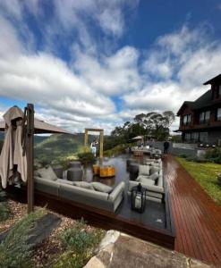 a living room with couches and an umbrella on a wooden deck at Hotel Château Du Golden in Gramado