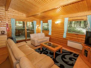 sala de estar con sofá, mesa y TV en Bamboo Retreat, en Legbourne
