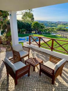 eine Terrasse mit 3 Stühlen, einer Bank und einem Tisch in der Unterkunft Da Silva Surfcamp 4 Bettzimmer mit Frühstück in Lourinhã