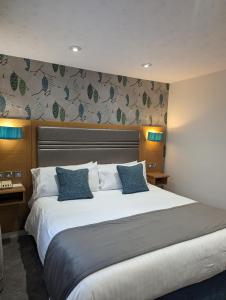 a bedroom with a large white bed with blue pillows at The Briar Court Hotel in Huddersfield