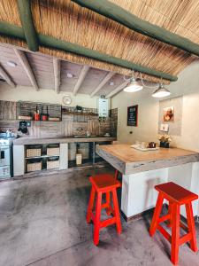 uma cozinha com dois bancos vermelhos e uma grande ilha em La Saucina - Cabaña Rústica Chic em Tunuyán