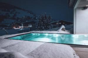 una piscina en la nieve por la noche en Haus Jausern, en Saalbach Hinterglemm